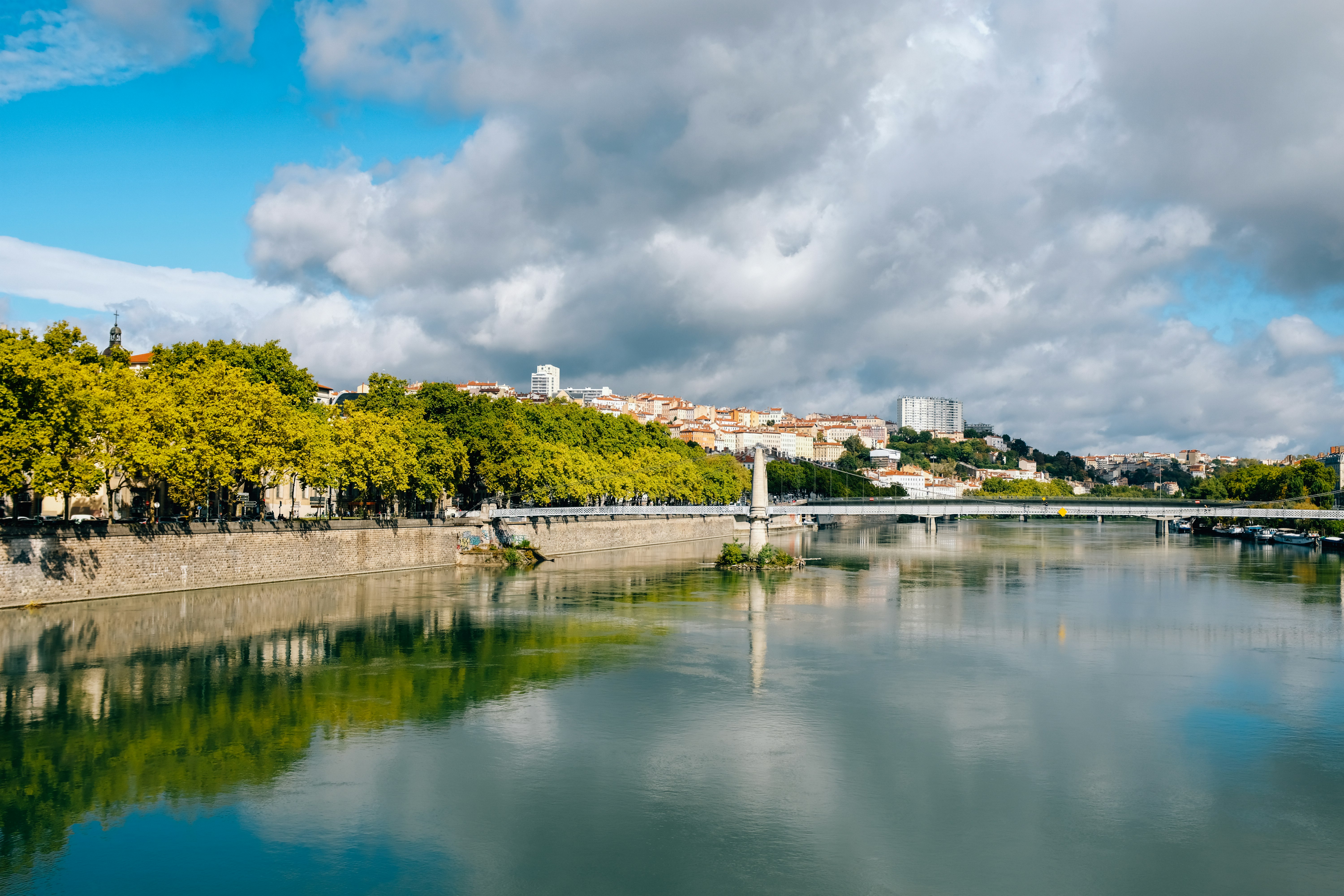 white and brown concrete building near body of water under white clouds and blue sky during